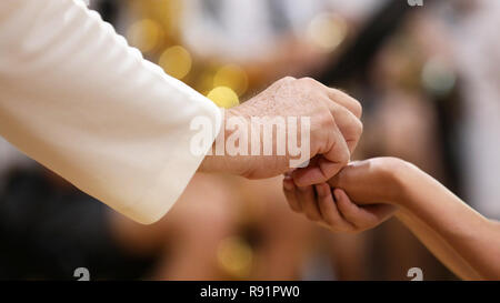 Close up image d'un paroissiens les mains jointes recevant le pain au cours de la sainte communion d'un prêtre catholique à la messe. Banque D'Images