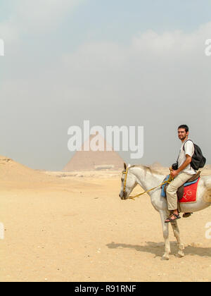 Les touristes à cheval dans le plateau de Gizeh près les pyramides de l'Égypte, Giza, Egypte. Autorisation modèle disponible Banque D'Images