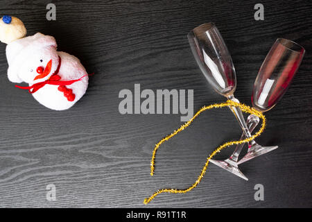 Deux verres de champagne décorée avec bonhomme de neige de Noël toy et un ruban d'or sur fond de bois. copy space Banque D'Images