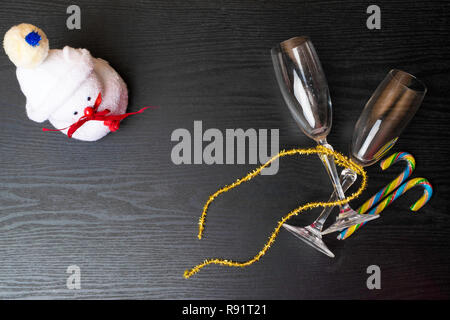 Deux verres de champagne décorée avec bonhomme de neige de Noël toy et un ruban d'or sur fond de bois. copy space Banque D'Images