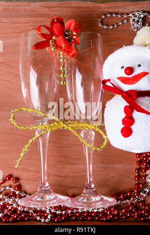 Deux verres de champagne décorée avec bonhomme de neige de Noël toy et un ruban d'or sur fond de bois. copy space Banque D'Images