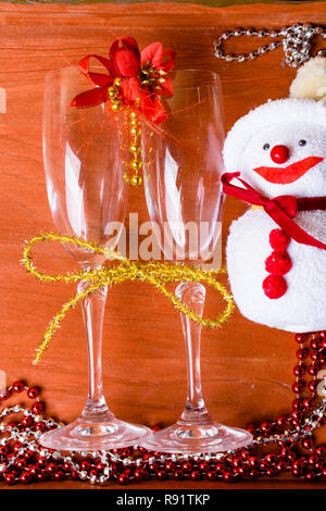 Deux verres de champagne décorée avec bonhomme de neige de Noël toy et un ruban d'or sur fond de bois. copy space Banque D'Images