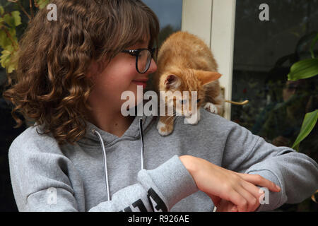 12 ans, fille au gingembre et chaton blanc de grimper sur son épaule Surrey England Banque D'Images