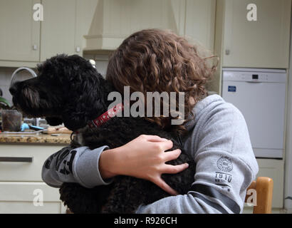 Douze ans Girl Hugging Dog Surrey Angleterre un cockapoo Banque D'Images