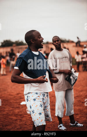 Mali, Afrique - jeune homme noir portant un t-shirt blanc tout en uniforme noir jouer au soccer avec les enfants, les garçons et les bénévoles du Caucase dans une ru Banque D'Images