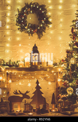 Salle de séjour, les jouets en bois, les figures, les étoiles, l'orignal, l'arbre de la fourrure sur la table en face de la cheminée décorée avec lanterne, boules de Noël avec des guirlandes, des lumières, des bougies, selective focus, tonique Banque D'Images