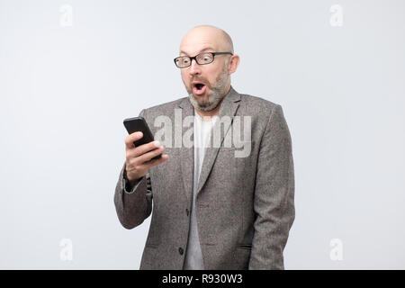 Stupéfait l'homme lit les nouvelles inattendues sur téléphone mobile en ligne Banque D'Images