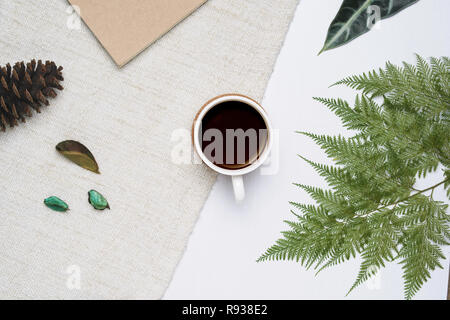 Tasse de café en bois blanc et brun sur fond de fils avec des fougères tropicales. Un minimum de mise à plat, vue du dessus. Banque D'Images