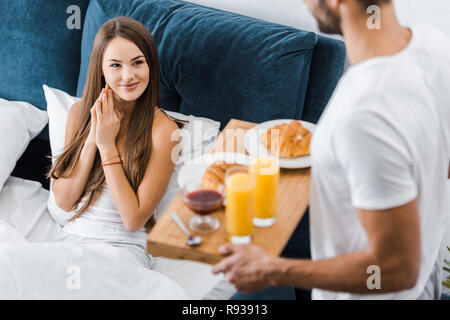 Young smiling woman looking at copain avec petit déjeuner sur plateau en bois Banque D'Images