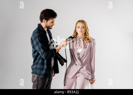 Jeune photographe à l'aide de posemètre et travailler avec beau modèle en studio Banque D'Images