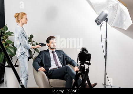 Le jeune photographe à l'aide de posemètre, tout en travaillant avec de beaux modèle masculin en studio Banque D'Images