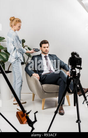 Le jeune photographe à l'aide de posemètre, tout en travaillant avec handsome businessman in studio Banque D'Images