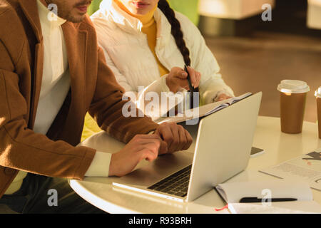 Portrait de l'homme et girl sitting at table with laptop in cafe Banque D'Images