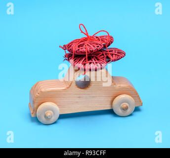 Petite voiture pour enfants en bois en osier porte un cœur rouge sur fond bleu Banque D'Images