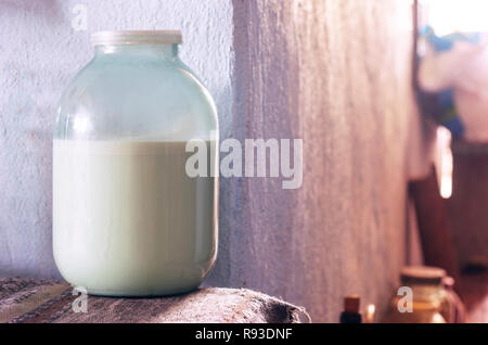 Avec couche de crème de lait frais dans un bocal en verre avec bouchon en plastique sur un tapis. Murs peints, rougeoyant soleil du matin à travers une fenêtre. L'agriculture biologique, des Banque D'Images