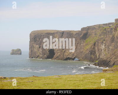 Vue sur mer avec la péninsule de Dyrhólaey et arches pile la mer dans le sud de l'Islande, avec en premier plan la falaise Banque D'Images