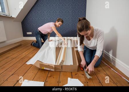 Mère et fille qui travaille ensemble pour former un lit double dans la chambre, lit fille jeux de montage, Allemagne Banque D'Images