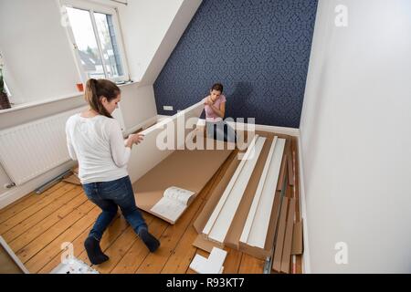 Mère et fille qui travaille ensemble pour former un lit double dans la chambre, lit fille jeux de montage, Allemagne Banque D'Images