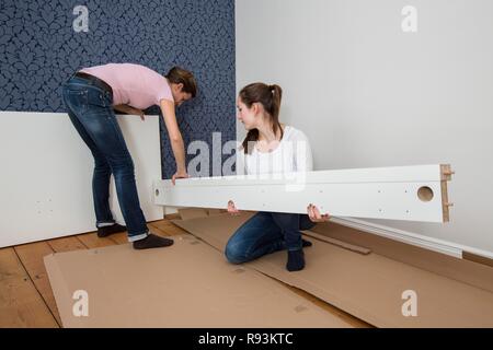 Mère et fille qui travaille ensemble pour former un lit double dans la chambre, lit fille jeux de montage, Allemagne Banque D'Images