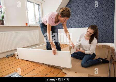 Mère et fille qui travaille ensemble pour former un lit double dans la chambre, lit fille jeux de montage, Allemagne Banque D'Images