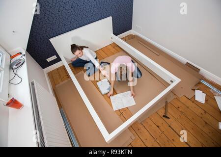 Mère et fille qui travaille ensemble pour former un lit double dans la chambre, lit fille jeux de montage, Allemagne Banque D'Images