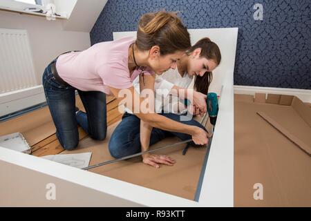 Mère et fille qui travaille ensemble pour former un lit double dans la chambre, lit fille jeux de montage, Allemagne Banque D'Images