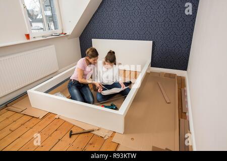 Mère et fille qui travaille ensemble pour former un lit double dans la chambre, lit fille jeux de montage, Allemagne Banque D'Images