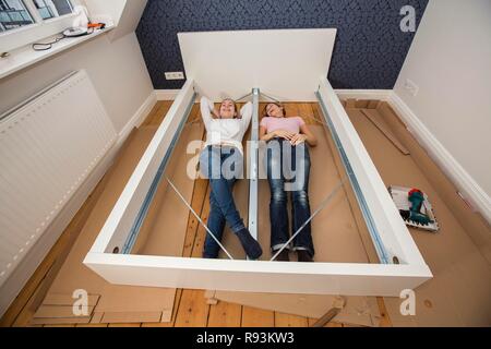 Mère et fille qui travaille ensemble pour former un lit double dans la chambre, lit fille jeux de montage, Allemagne Banque D'Images