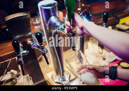 Jeune femme en bar bière distribution de robinets en métal. Belle female bartender touchant la bière dans un bar. Banque D'Images