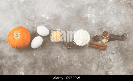 Ingrédients pour tarte à la citrouille - farine, les citrouilles, les oeufs, le sucre de canne, épices diverses (muscade, gingembre, cannelle, anis) sur un fond gris. Vue d'en haut. L'alimentation Banque D'Images