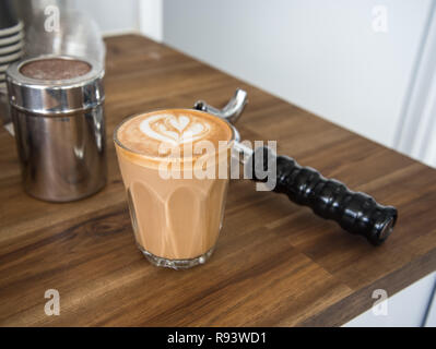 Latte Café art sur un banc avec outils machine à café autour de lui. Cafe latte avec un coeur sur elle, belle boisson chaude