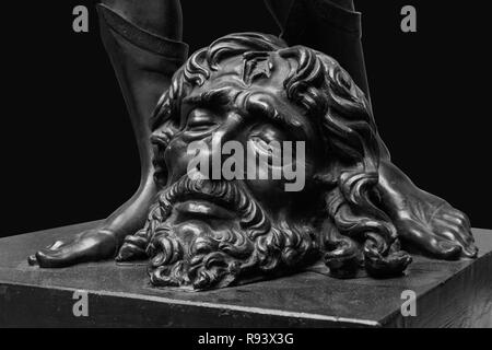 Les jambes de David avec la tête de Goliath, statue isolé sur noir. Banque D'Images