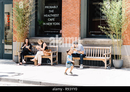 La ville de New York, USA - 25 juin 2018 : Les gens assis sur des bancs appréciant le déjeuner au café de devanture de Greene Street à Soho historique Fonte Distric Banque D'Images