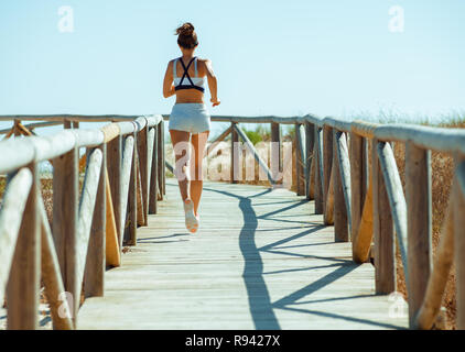 Vus de derrière, les sports actifs femme en vêtements de sport sur la côte de l'océan. jogging côte de l'océan superbe endroit pour faire votre entraînement. fonctionnant sur un air frais d'un Banque D'Images