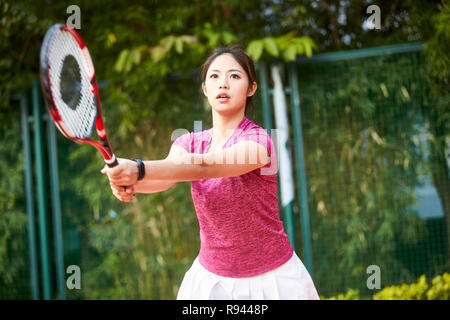 Young Asian woman playing tennis outdoors Banque D'Images