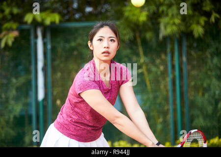 Young Asian woman tennis player hitting ball avec revers Banque D'Images