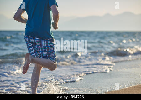 Barefoot man pendant le jogging sur une plage Banque D'Images