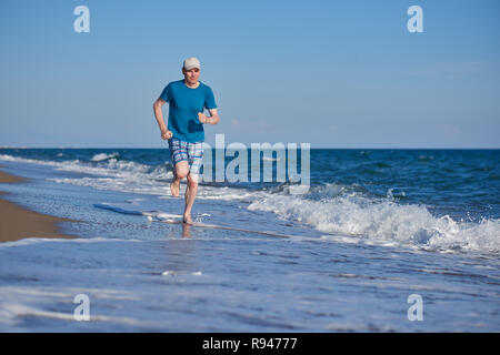 Barefoot man pendant le jogging sur une plage Banque D'Images