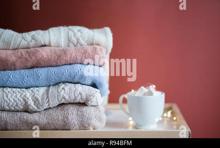 Une pile de pulls d'hiver pliée. Pile de pulls et une tasse de café, de l'espace pour le texte Banque D'Images
