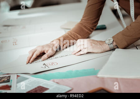 À partir d'un professionnel de l'école de mode avec une montre dans sa main en travaillant avec des croquis Banque D'Images