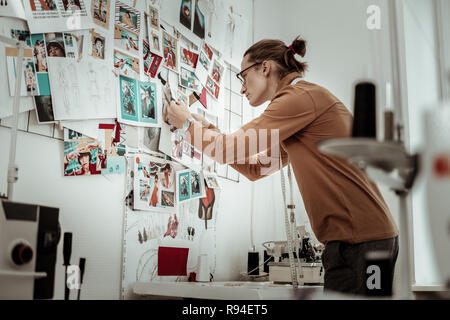 Styliste dans un vêtement brown mise sur un conseil d'une nouvelle vue. Banque D'Images