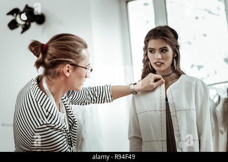 Grand beau modèle avec de grandes boucles d'essayer sur une nouvelle veste Banque D'Images