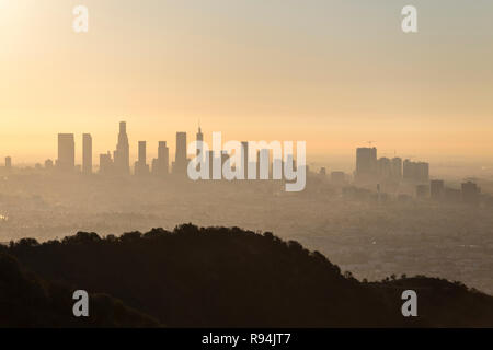 Orange brumeux dawn cityscape vue sur le centre-ville de Los Angeles, Hollywood avec Runyon Canyon Park colline en premier plan. Banque D'Images