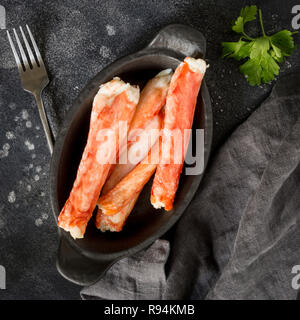 Les bâtonnets de crabe kamchatka de luxe sur la plaque noire avec le persil, fourchette et serviette à fond noir. Maison de lave Banque D'Images