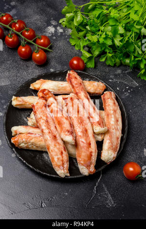 Les bâtonnets de crabe kamchatka de luxe sur la plaque noire avec le persil et les tomates cerise à fond noir. Maison de lave Banque D'Images