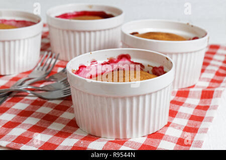 Des cordonniers de framboises et groseilles blanches dans le moule en céramique pour la cuisson sur table en bois blanc. L'accent peu profondes. Banque D'Images