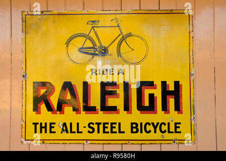 Vieux métal panneau publicitaire pour bicyclettes Raleigh sur l'affichage sur le mur à la gare Banque D'Images