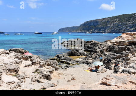 Bateaux au mouillage et les gens à prendre le soleil sur les rochers, Es Calo, Majorque, îles Baléares, Espagne Banque D'Images