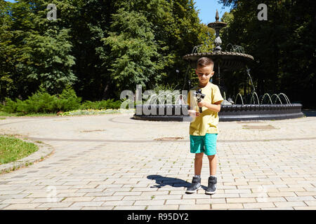 Jeune garçon en tenant sur l'action extérieure de l'appareil photo selfies et un cactus en arrière-plan. Portrait de l'adolescence avant de jouer avec action cam dans le jardin Banque D'Images