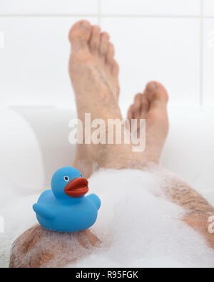 Les pieds des hommes dans une baignoire d'un blanc éclatant, selective focus sur les orteils Banque D'Images